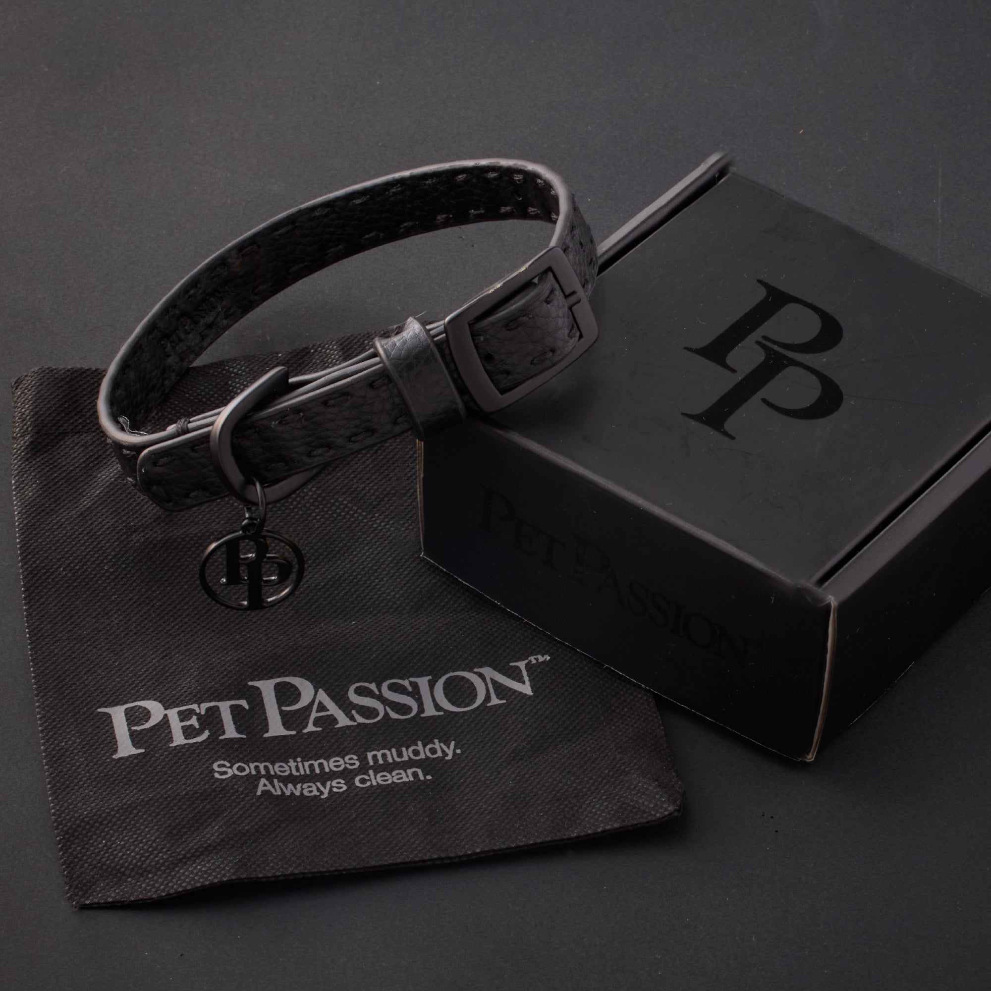 Rein collar in Black Beatuy with it's garment bag and packaging box, labeled with the Pet Passion logo and slogan, all on a black background