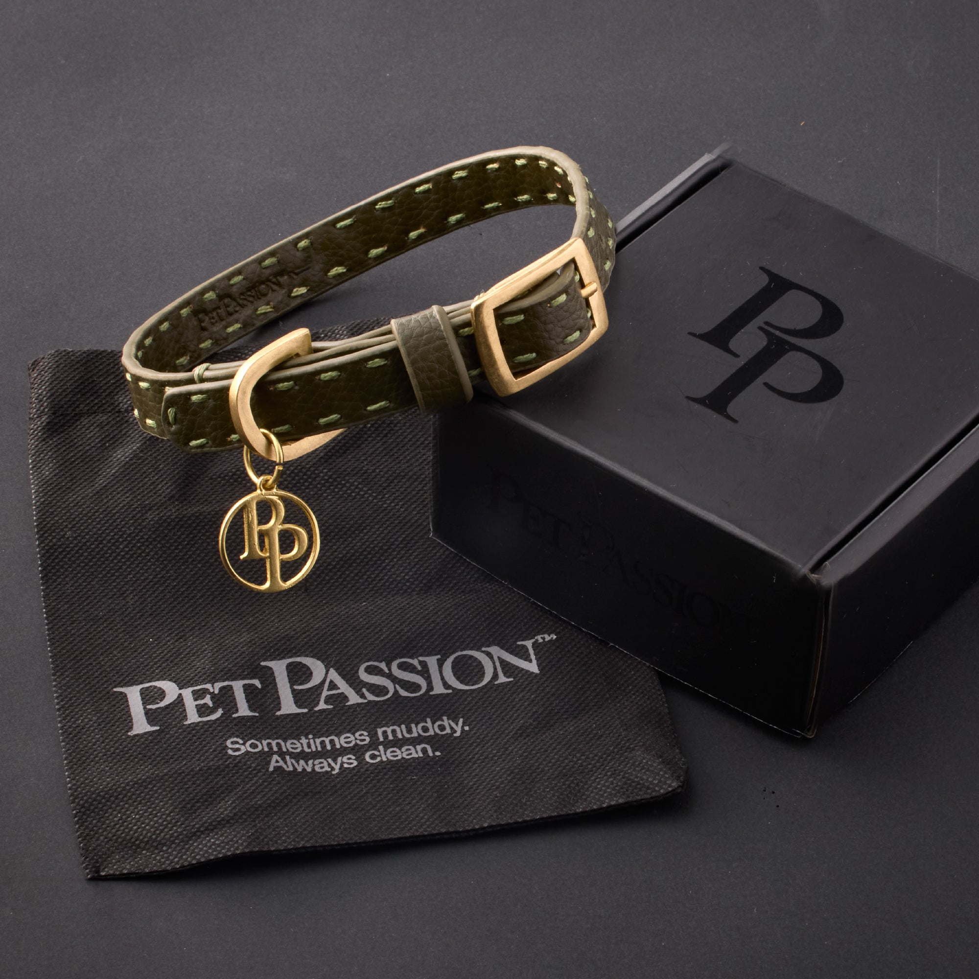 Rein collar in Scottish Olive with it's garment bag and packaging box, labeled with the Pet Passion logo and slogan, all on a black background