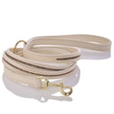 Beige dog leash with gold hardware on a white background