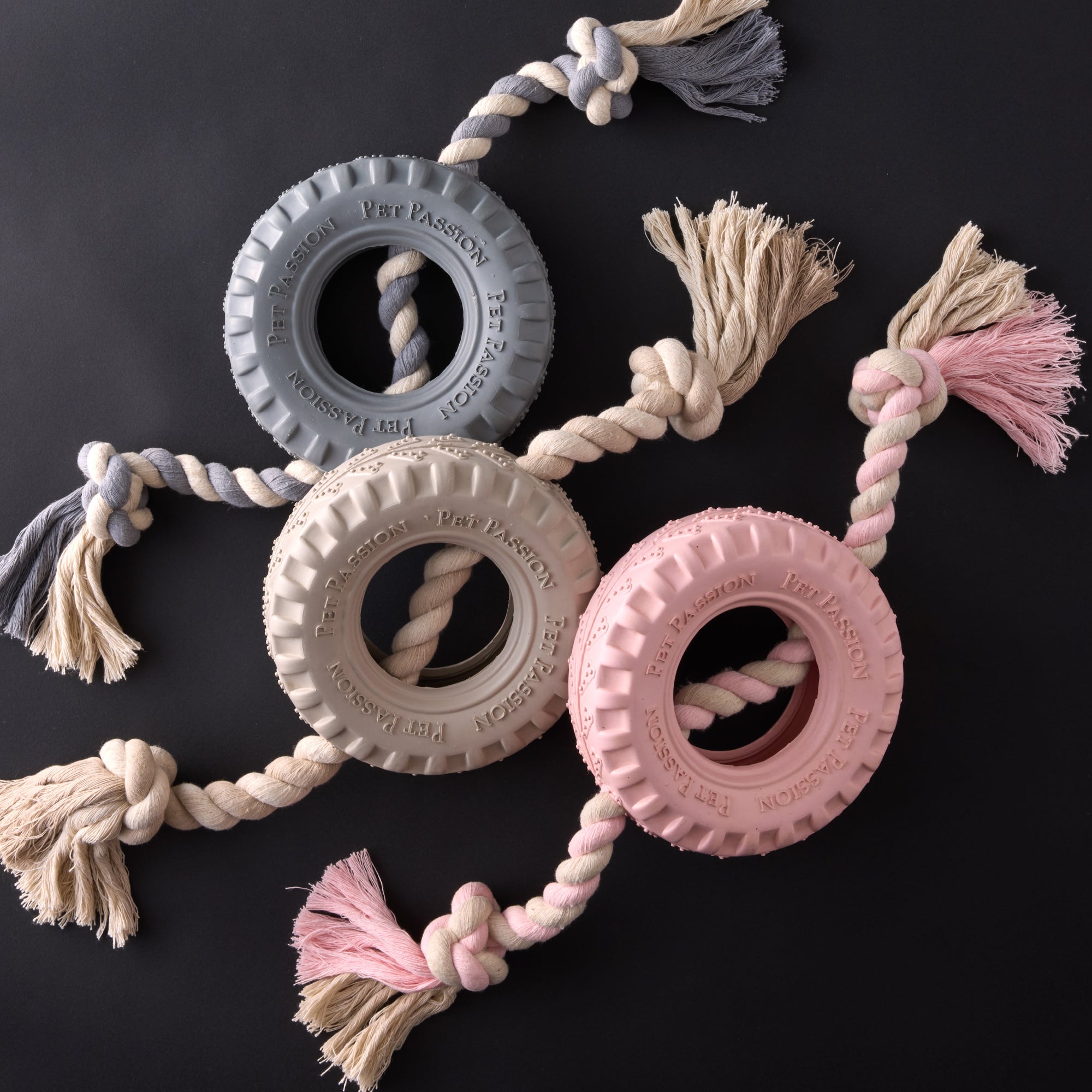 Blue, Beige, and pink tire tug toys on a black background