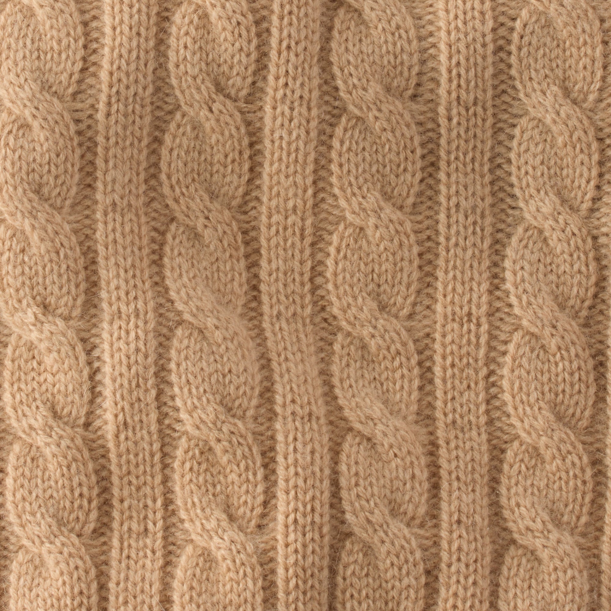 Close-up of beige knitted fabric with cable pattern