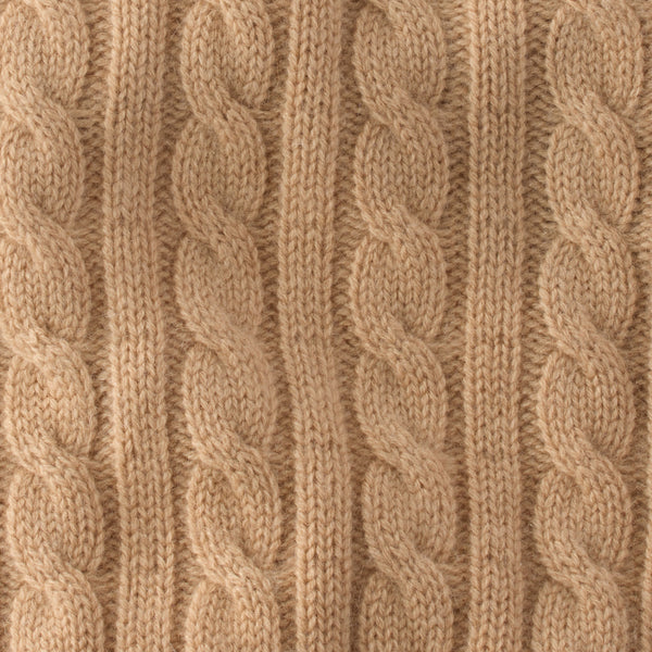 Close-up of beige knitted fabric with cable pattern