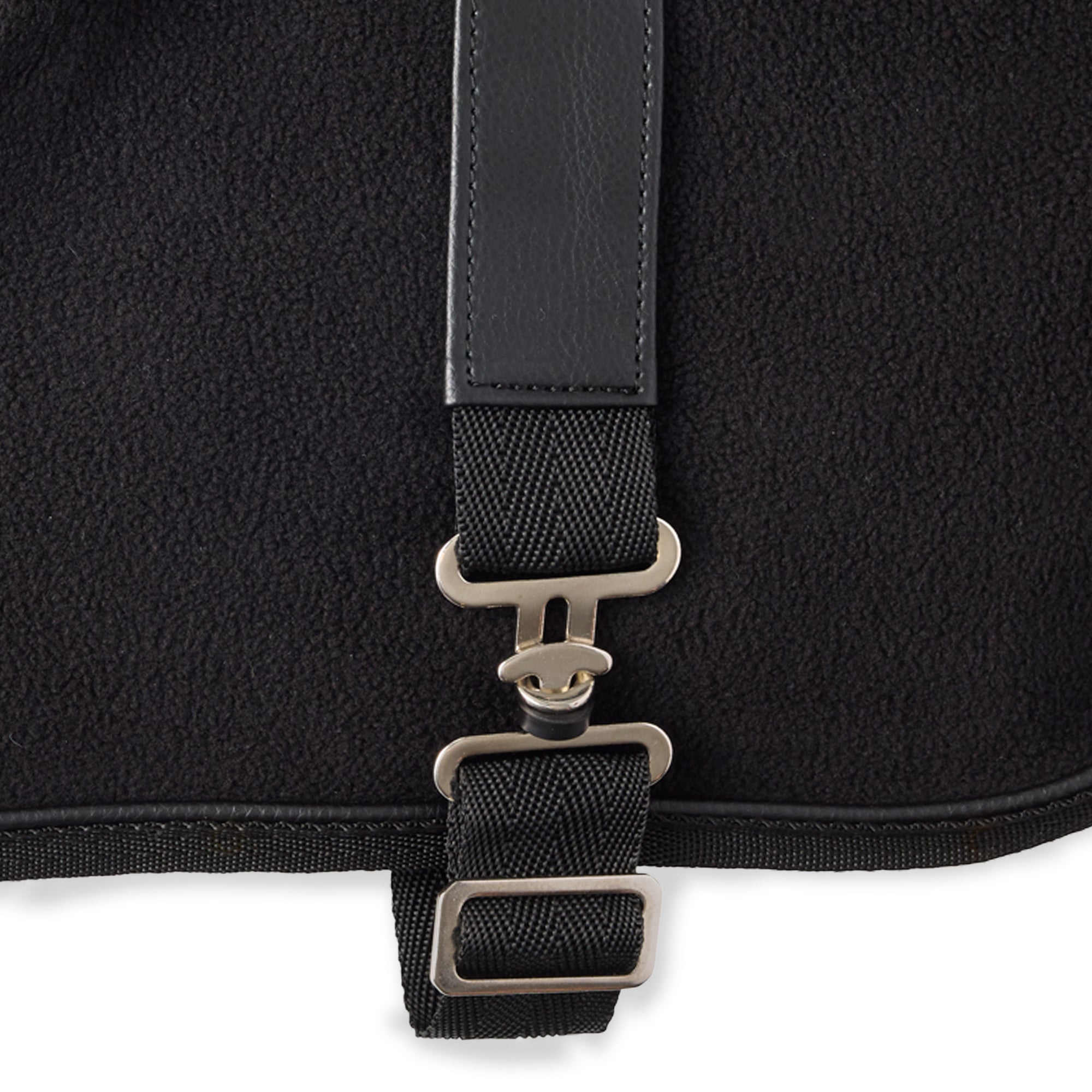 Close-up of a black dog coat with a strap and metal buckle on a white background