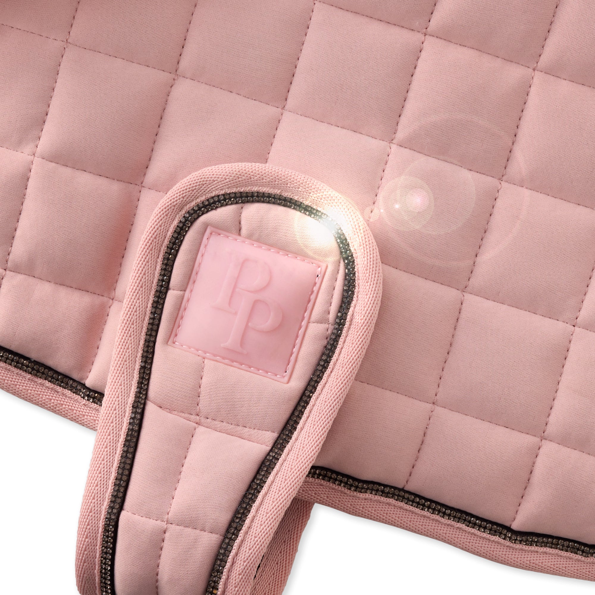 Close-up of a pink quilted saddle pad with a brand logo on a white background