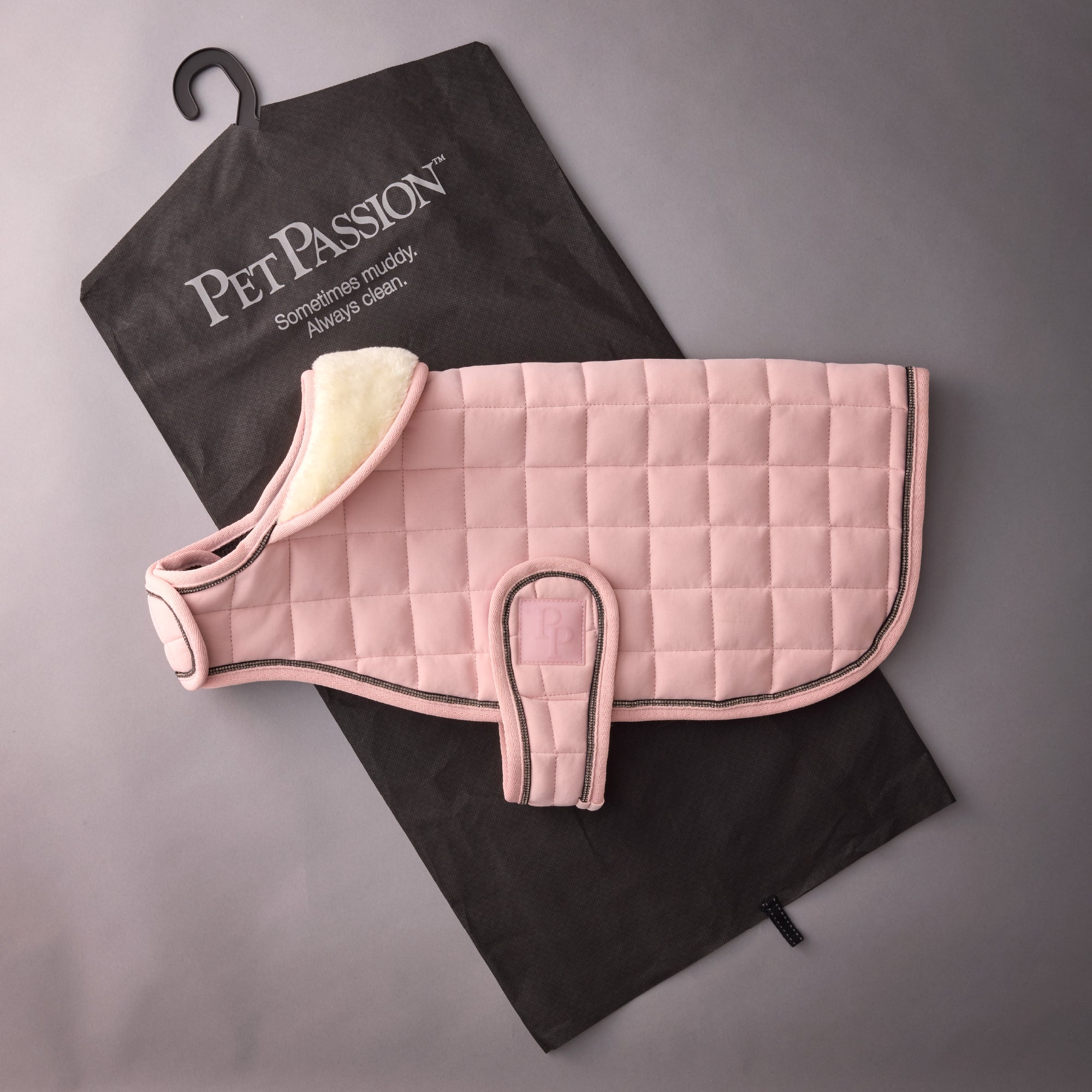 Pink quilted pet bed with a black towel labeled 'Pet Passion' on a gray background