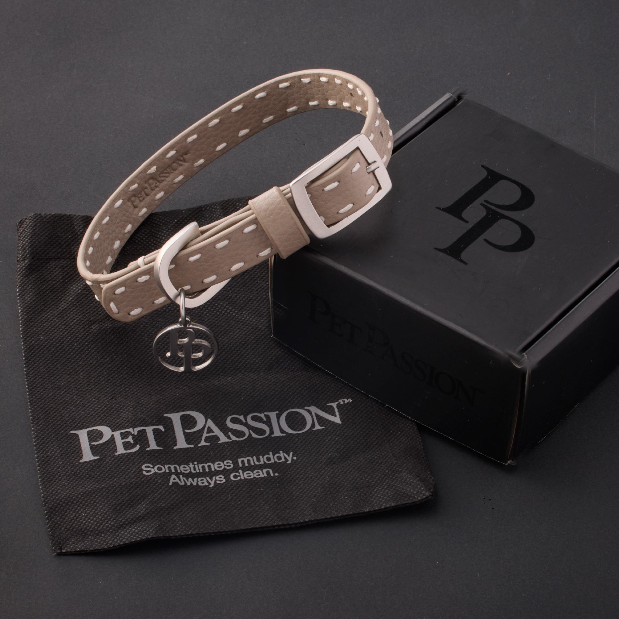 Rein collar in Dappled Cashmere
 with it's garment bag and packaging box, labeled with the Pet Passion logo and slogan, all on a black background
