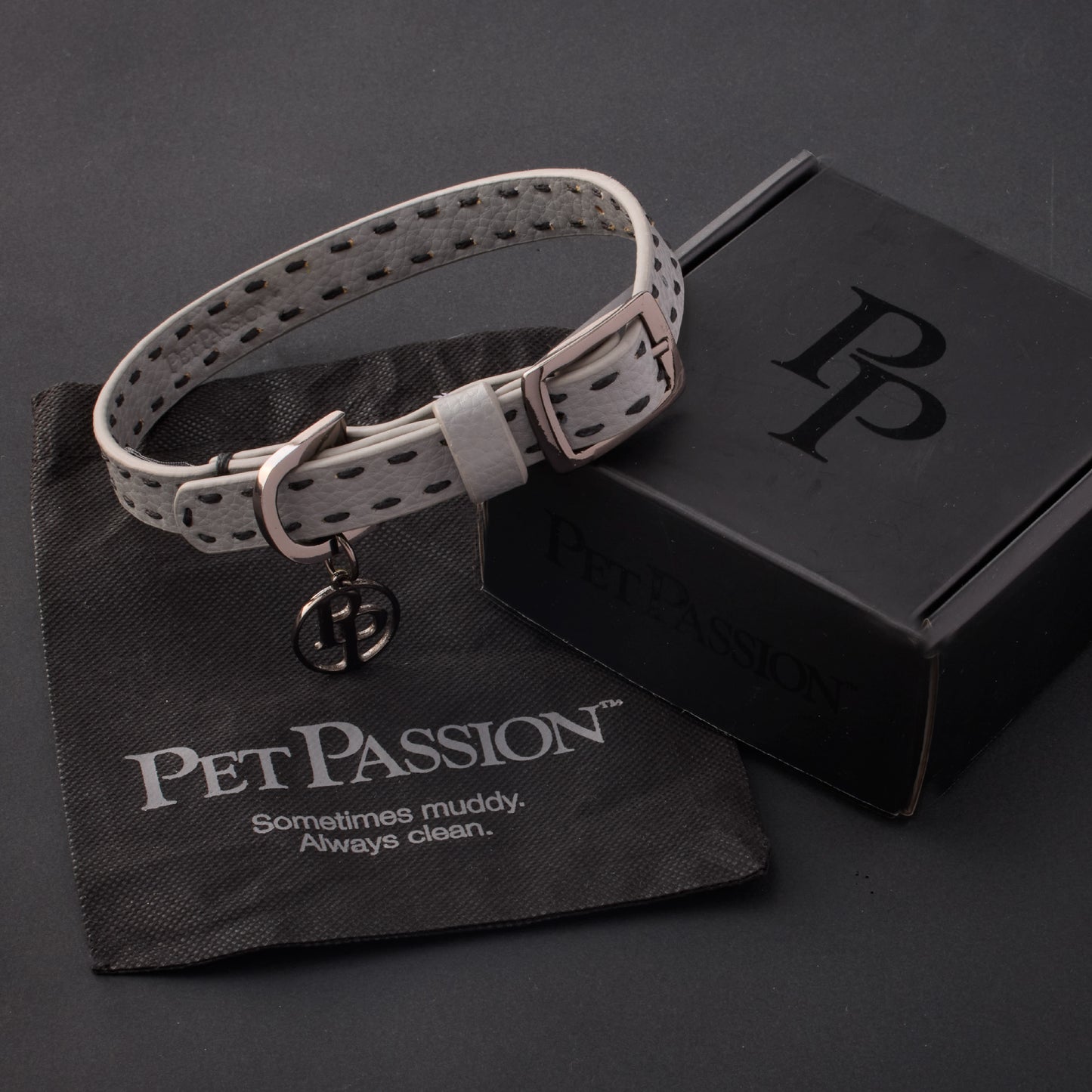 Rein collar in Gray with it's garment bag and packaging box, labeled with the Pet Passion logo and slogan, all on a black background