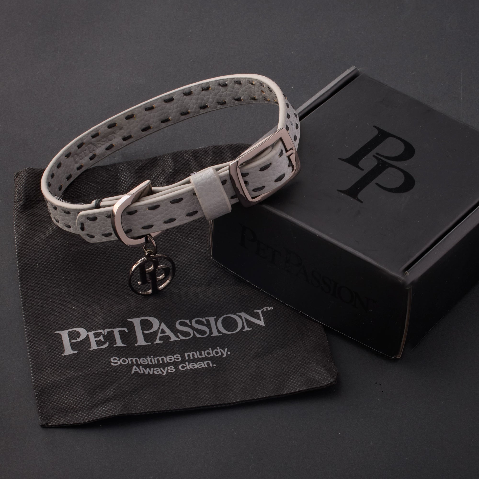 Rein collar in Gray with it's garment bag and packaging box, labeled with the Pet Passion logo and slogan, all on a black background