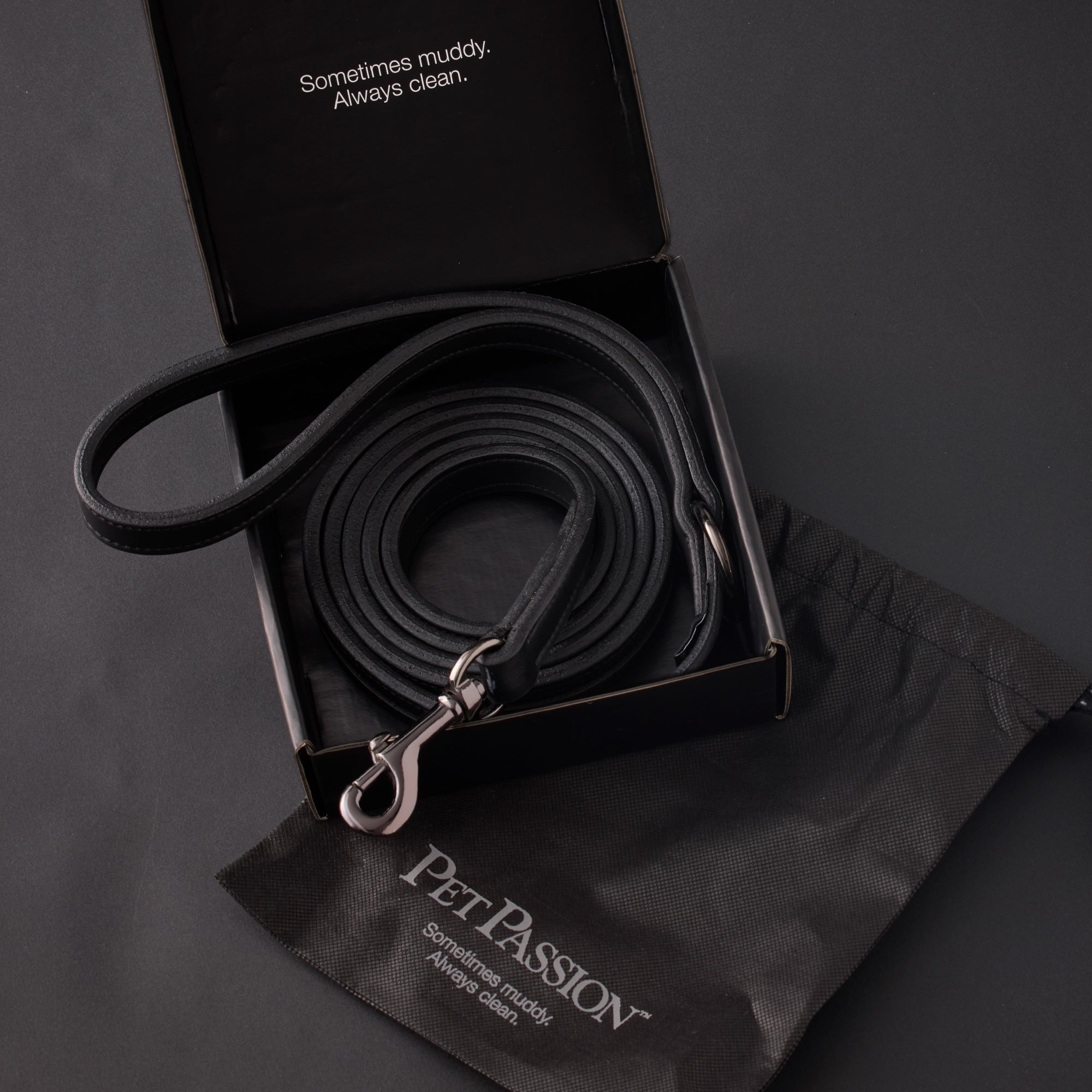 Black dog leash with metal clip in a black box on a dark background