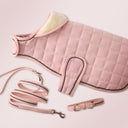 Pink quilted dog coat with matching leash and collar on a light pink background
