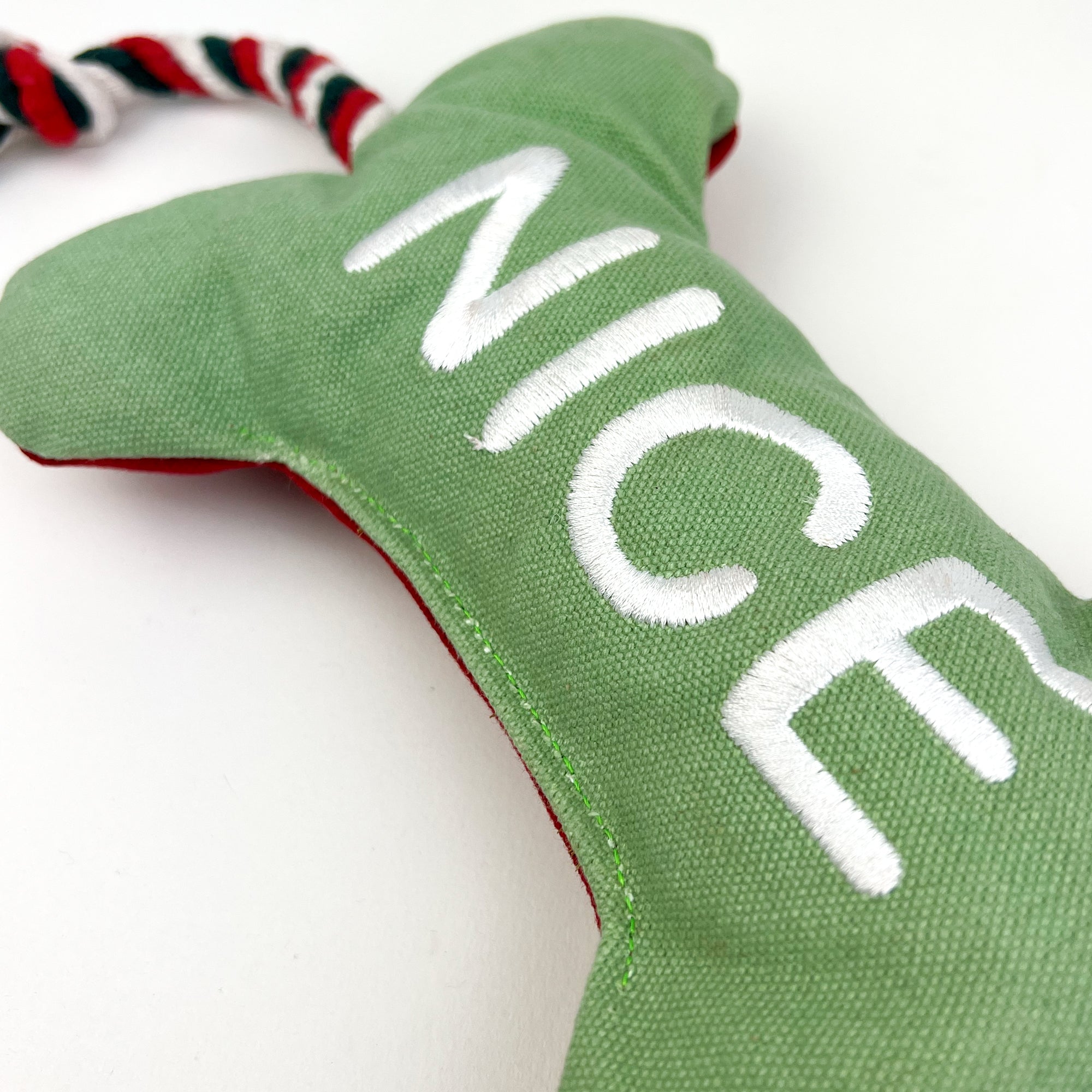 Bone dog toy with nice written on it on a white background