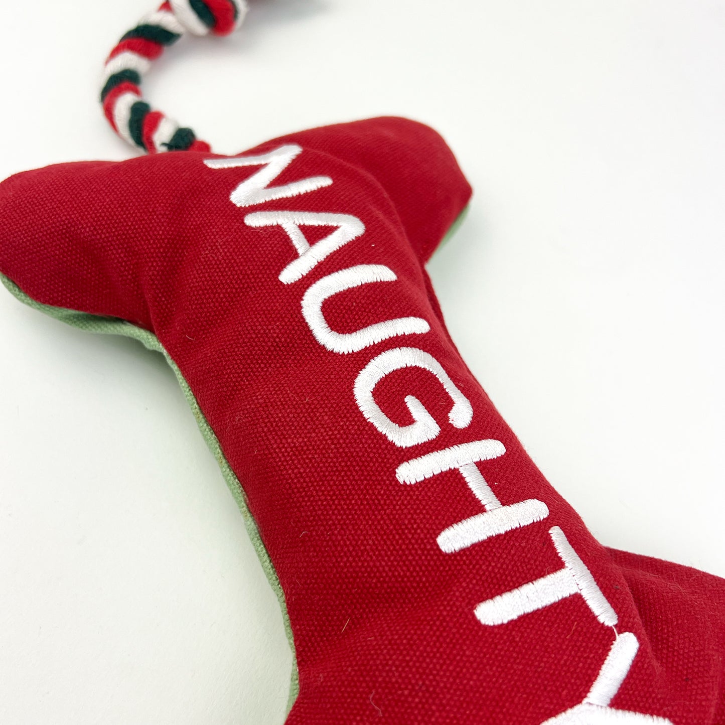 Bone dog toy with naughty written on it on a white background