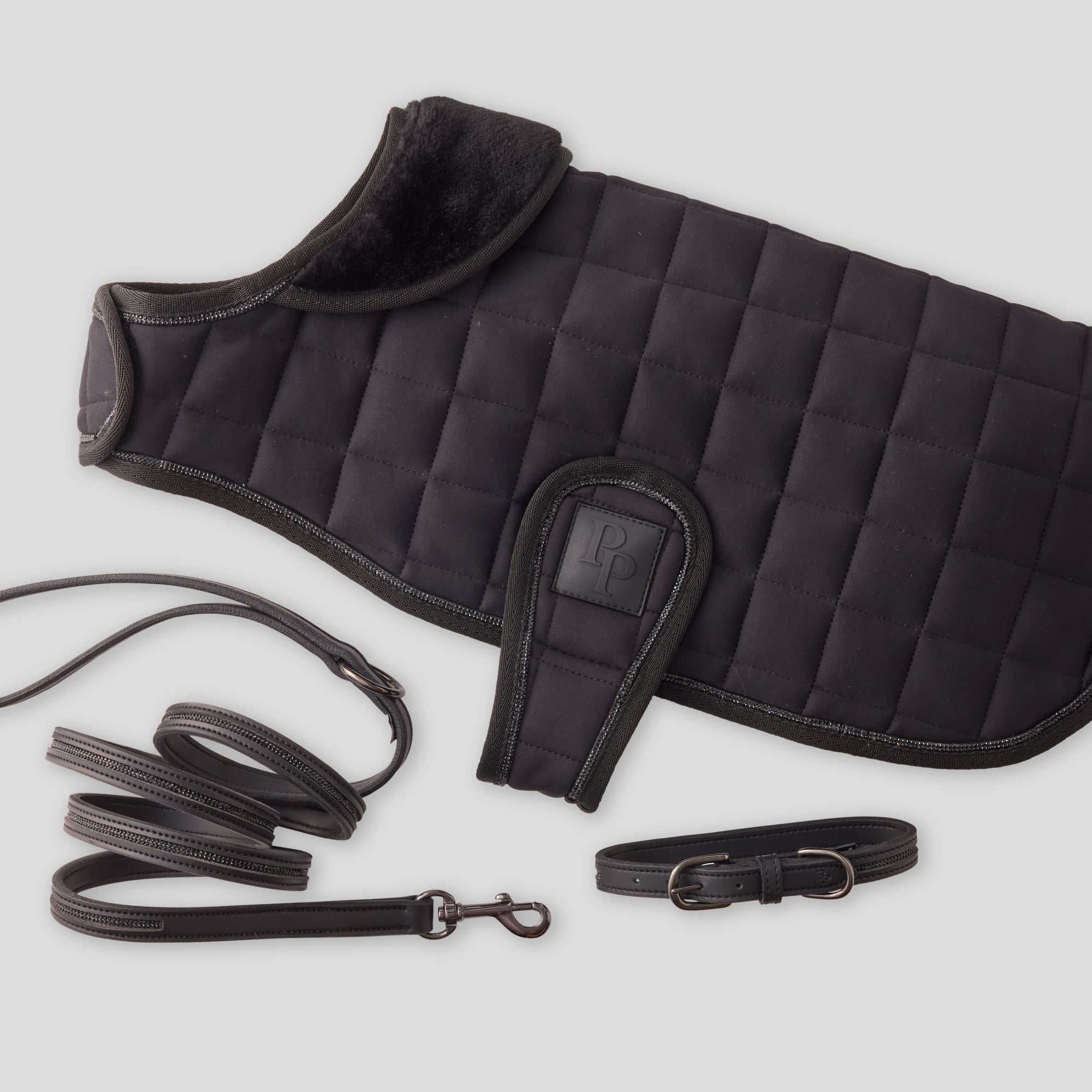 Black quilted dog coat with a leash and collar on a light gray background