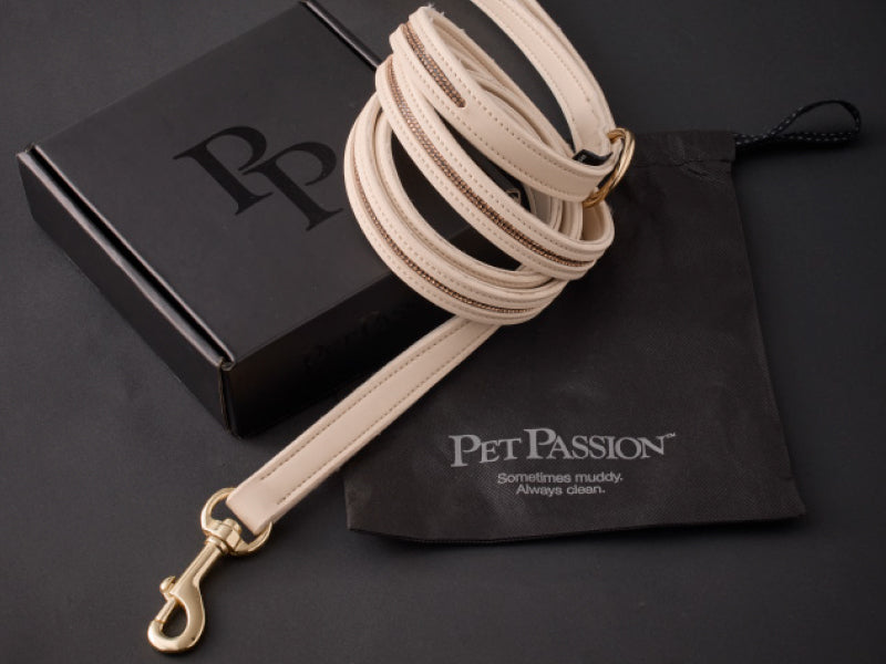 Beige dog leash with gold hardware on a black background with 'Pet Passion' branding.